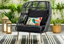 Lifestyle image of the Better Homes & Gardens Tarren Wicker Accent Chair in black set up outdoors