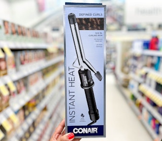 hand holding Conair Instant Heat Curling Iron in aisle