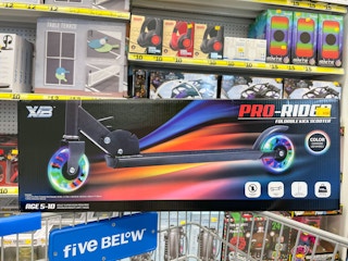 A foldable scooter sitting atop a Five Below shopping cart.