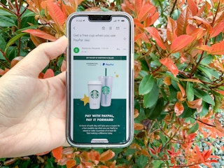 Someone holding a phone displaying the Starbucks offer for Earth day
