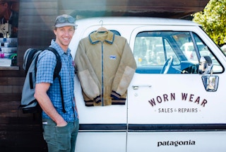 A man standing next to a Patagonia jacket hanging off of the Patagonia Worn Wear truck.