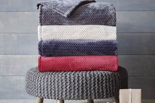 s stack of flannel blankets in different colors on a stool