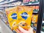 hand holding two pedigree pouches in walmart aisle