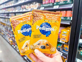 hand holding two pedigree pouches in walmart aisle