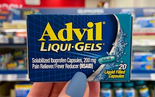 A person's hand holding up a box of advil liquid gels in store.