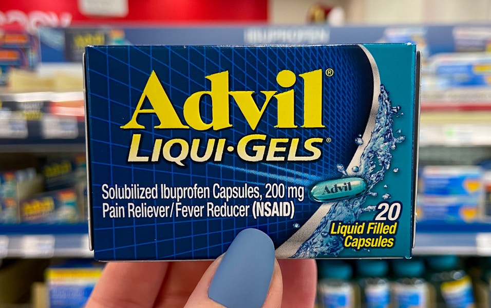 A person's hand holding up a box of advil liquid gels in store.