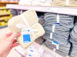 hand holding a room essentials washcloth set in front of a target shelf