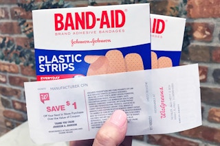 Someone holding some boxes of Band Aids with a catalina coupon from Walgreens
