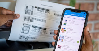 person printing coupons and holding phone with coupons.com app