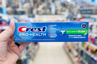 hand holding crest toothpaste in store aisle
