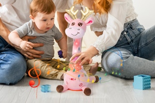 Baby watching the LLUKEME Dancing Talking Giraffe next to their parents on the floor.