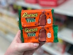A person's hand holding two Reese's peanut butter tree chocolate treats.