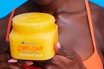 Woman holding jar of Tree Hut Golden Sand sugar scrub