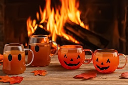 Lifestyle image of the Way to Celebrate Halloween Glass Mugs (Ghost & Pumpkin) AI image created by ChatGPT with fire in the background