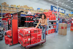 A woman pushing a cart loaded with craftsman tools at Lowe's