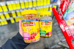 person holding 2 nature made vitamin bottles