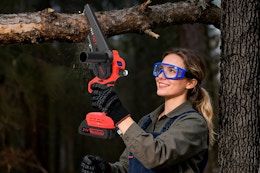 Lifestyle image of the UNTIMATY 6-inch Mini Chainsaw being used to cut a tree branch