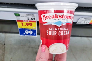 hand holding a container of breakstones sour cream at kroger