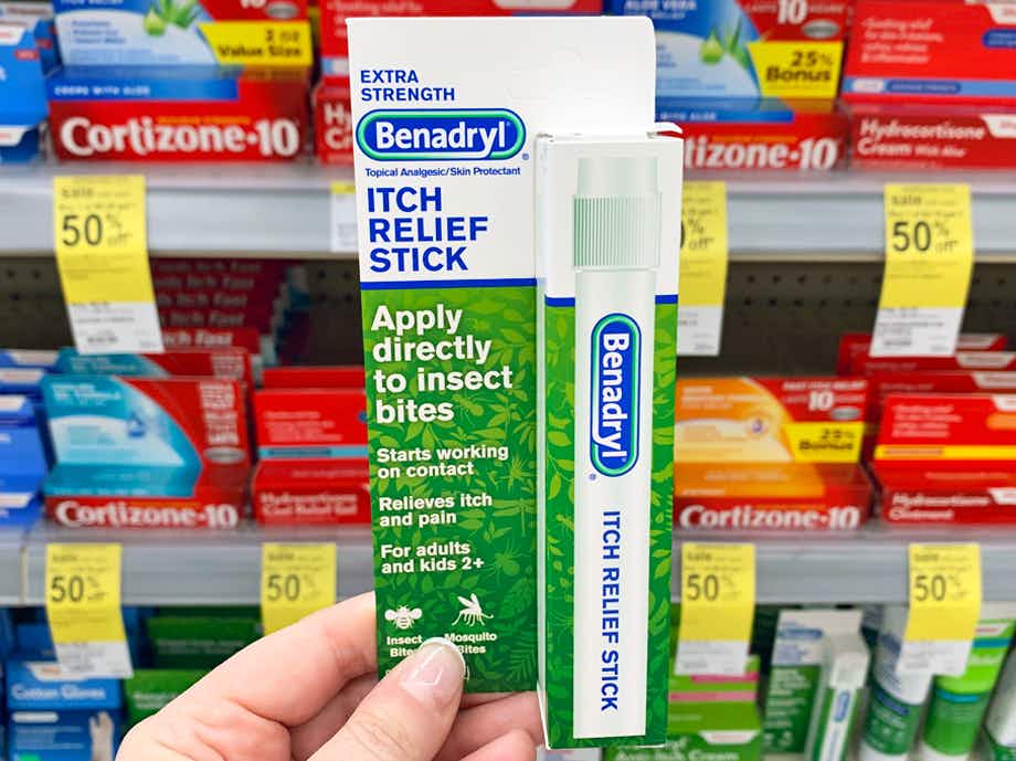 A person's hand holding up a package of a Benadryl itch relief stick in store.