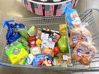 A cart filled with grilling essentials parked in front of some americana decor at Walmart