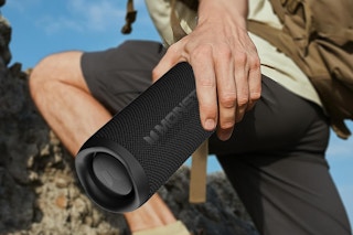 man carrying bluetooth speaker up a mountain