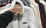 a woman's hand holding the Patagonia tag on a Patagonia fleece zip up at dick's sporting goods