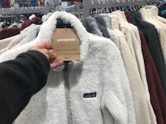 a woman's hand holding the Patagonia tag on a Patagonia fleece zip up at dick's sporting goods