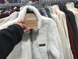 a woman's hand holding the Patagonia tag on a Patagonia fleece zip up at dick's sporting goods