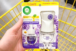 hand holding an air wick starter kit above a yellow shopping cart