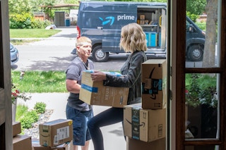 a woman getting a box from an amazon delivery man
