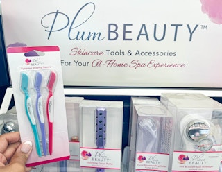 hand holding pack of Plum Beauty eyebrow shaping razors in front of display