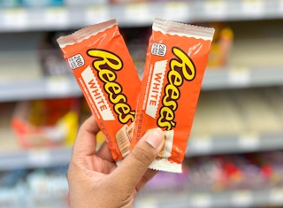 hand holding two packs of Reese's peanut butter cups candy in aisle