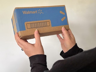 Someone holding up a box shipped from Walmart.com