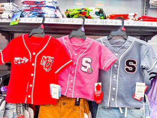 three toddler baseball jerseys hanging on walmart shelf