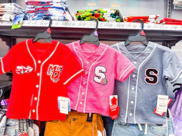 three toddler baseball jerseys hanging on walmart shelf