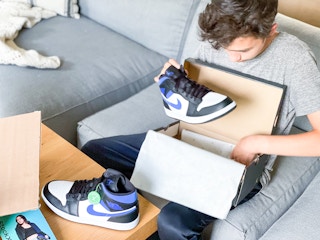 boy pulling nike sneaker out of box