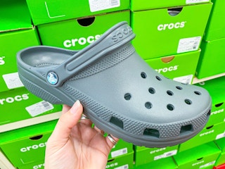 hand holding a Crocs clog in front of shoe boxes