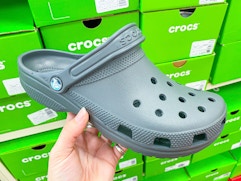 hand holding a Crocs clog in front of shoe boxes