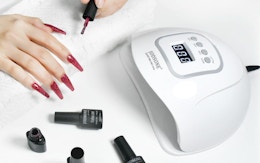 a person paint their nails next to a nail lamp