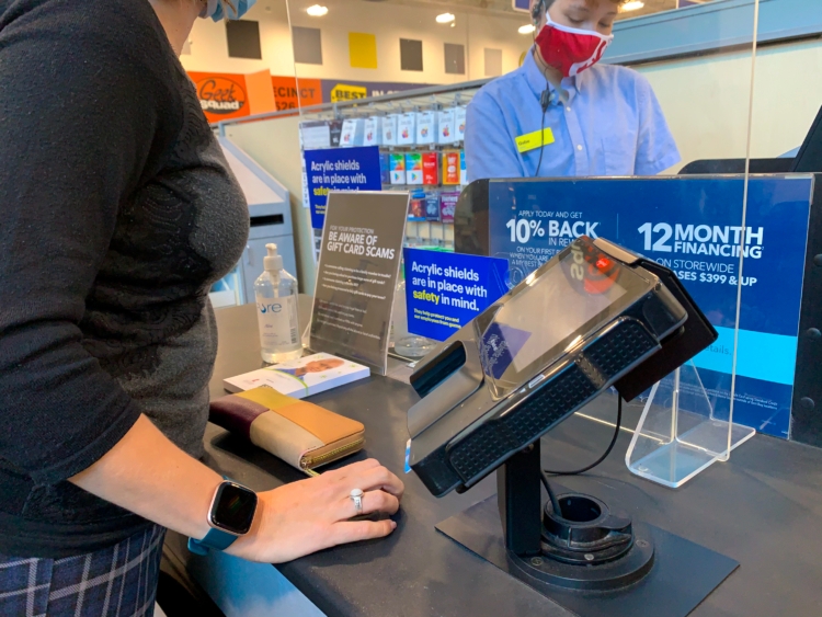 A person standing at a Best Buy checkout counter while an employee rings them up.