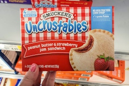 hand holding a box of smuckers uncrustables at kroger