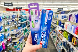 hand holding crest toothpaste and oral-b toothbrush