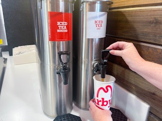 a person filling an arbys drink cup with iced tea