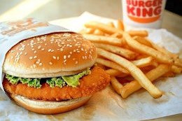 A chicken sandwich next to some fries and a burger king fountain drink