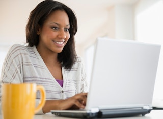 woman sitting and working on laptop with coffee