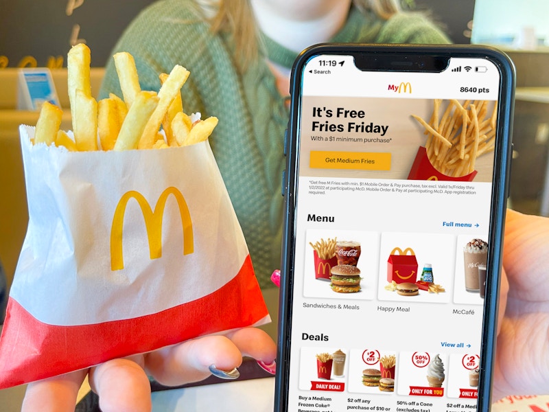 women holding cellphone with mcdonalds app and french fries