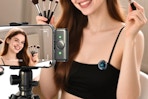 woman recording herself applying makeup and talking while wearing a microphone