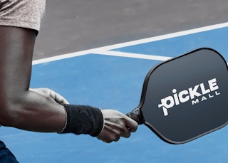 A man holds a Pickle Mall branded pickleball paddle.
