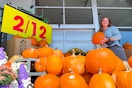 A woman holding a pumpkin in front of the kroger pumpkin display 