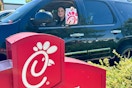 a woamn in a car holding out a chick fil a bag